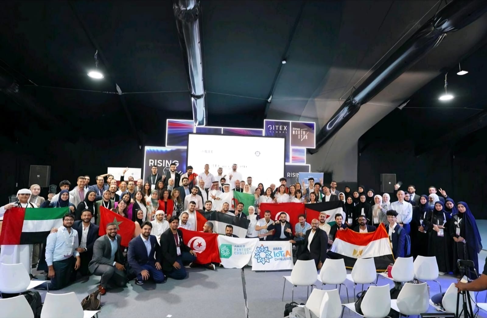 The Arab IoT & AI Challenge finalists gathered on stage at GITEX Global, holding their countries' flags and the challenge banner.